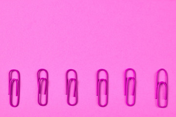 Pink paper clips isolated on pink background, close up, copy space. Top view, flat lay. Back to school, college, education concept