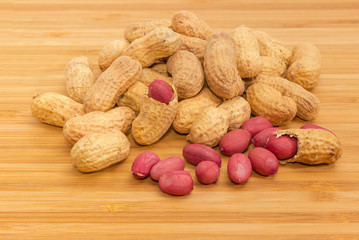 Pile of the partly peeled roasted peanuts on wooden surface