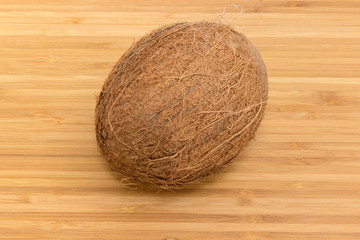 Whole coconut fruit on a bamboo wooden surface