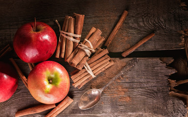 Cinnamon sticks and ripe apples on a wooden background. Low key lighting