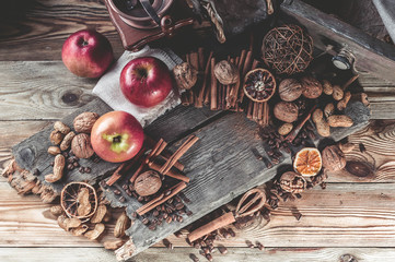 Nuts, cinnamon sticks, coffee beans, coffee grinder and ripe apples on a wooden background. Easy toning. Close-up. Top view