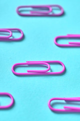 Violet paper clips isolated on turquois background, close up, copy space. Top view. Back to school, college, education concept