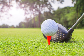 Golf clubs and golf balls on red tee.