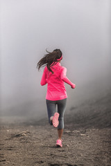 Run fit woman runner running on trail path in mountains in fog and clouds - morning jogging...