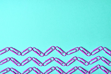 Violet (purple) paper clips on turquois background, close up, copy space for text. Top view, flat lay. Back to school, college, education concept. Waves made from paperclips