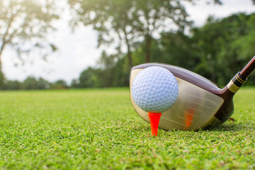 Golf clubs and golf balls on red tee.