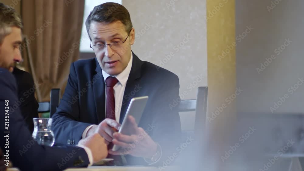Poster tracking shot of three business people using tablet computer to discuss future agreement at meeting 