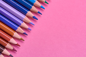 Color pencils on pink pastel background, close up. Set of colorful pencils, copy space. Crayons. Top view, flat lay. Back to school, college concept. Abstract background