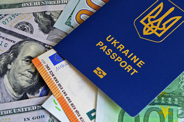 The Ukrainian biometric passport is on paper euro bills and dollars. Concept: increase of salaries, Ukrainians go abroad to work in Europe, Immigration to work, vacation abroad, visa for Europe.