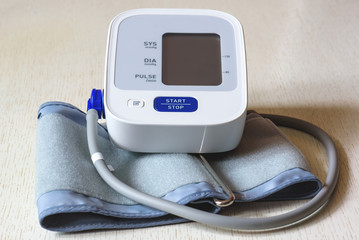 White electronic tonometer close-up on a wooden table. Measurement of blood pressure. Healthy...