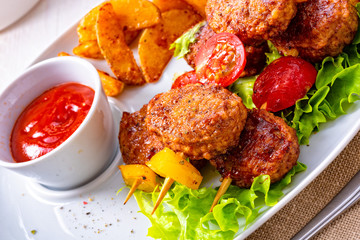 Meatballs skewers of tomato, paprika and baked potato quarters