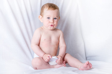 Cute blue-eyed baby 6-9 months smiling and playing on white background. Cleanliness and care for babies