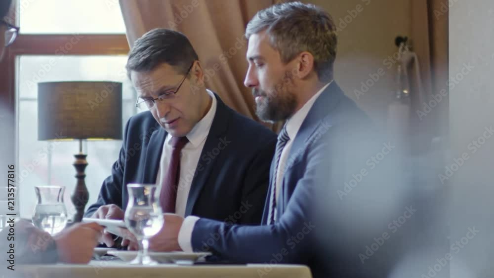 Aufkleber tracking shot of business people using tablet computer when discussing potential partnership at meet
