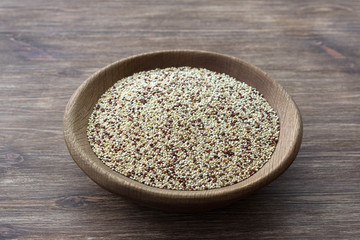 Mixed raw quinoa in wooden bowl on wooden table. Healthy, gluten free superfood