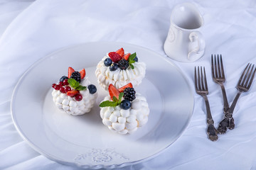 Obraz na płótnie Canvas Delicate white meringues with fresh berries on the plate. Dessert Pavlova. White background. Wedding cake.