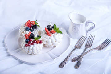 Delicate white meringues with fresh berries on the plate. White background. Wedding cake.