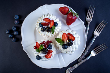 Delicate white meringues with fresh berries on the plate. Dessert Pavlova close-up. Wedding cake.