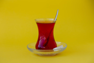Glass of Turkish tea on yellow background