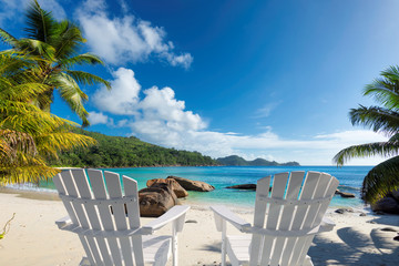 Beach chairs on sandy beach with palm and turquoise sea.  Summer vacation and travel concept.  