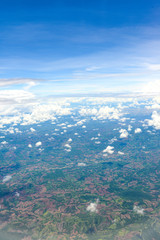 Beautiful view of blue sky above the white clouds and land background from airplane window