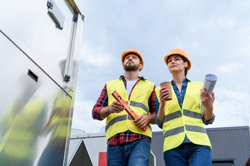 architects in helmets with blueprint coffee and level on roof