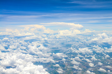 Beautiful view of blue sky above the white clouds and land background from airplane window
