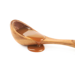 Wooden spoon of caramel sauce isolated