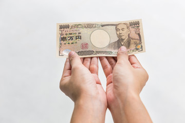 Businesswoman giving money and holding 10,000 japanese yen money in hand Isolated on white background, Japanese yen financial and business concept