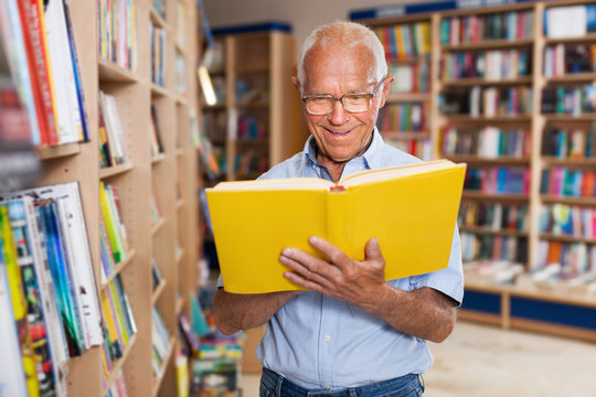 Older man reader browsing inside of books in bookshop