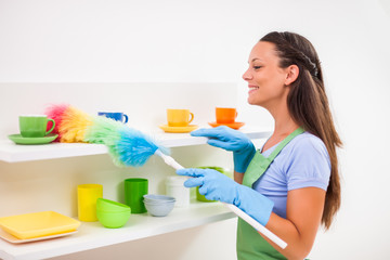 Young happy woman is cleaning the kitchen.