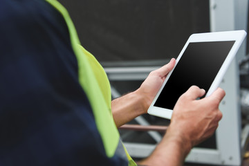 cropped view of worker in safety vest using digital tablet with copy space