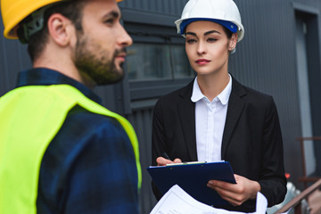 selective focus of architect and builder in helmets working on construction