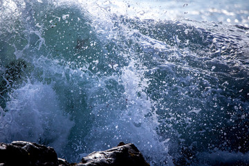 Fototapeta na wymiar White foamy waves crash and break onto the rocky coastline