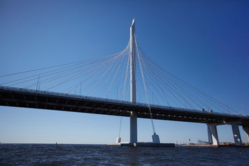 Fototapeta na wymiar Beautiful urban high bridge with twisted steel wire ropes crossing river in big city