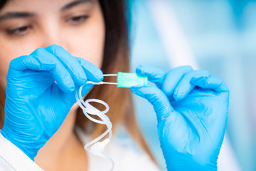 technician girl with microfluidic device LOC in microbiological lab