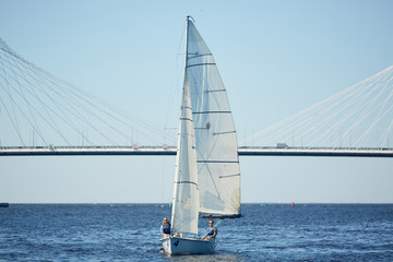 Fototapeta premium Beautiful sailboat with men on deck floating on river