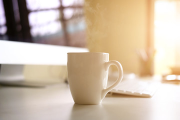 Mug of coffee on office workplace with morning coffee concept.