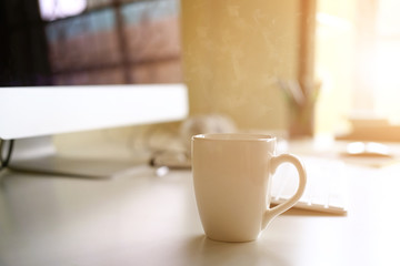 Mug of coffee on office workplace with morning coffee concept.