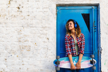 Fototapeta na wymiar Portrait of beautiful young woman holding long-board skateboard
