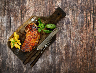 grilled steak on a cutting board on a wooden background. Top view.