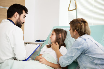 Fototapeta premium Doctor talking with patient girl in hospital room 