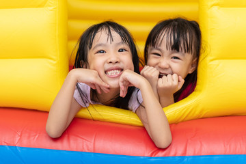 Asian Little Chinese sisters playing at inflatable castle - Powered by Adobe