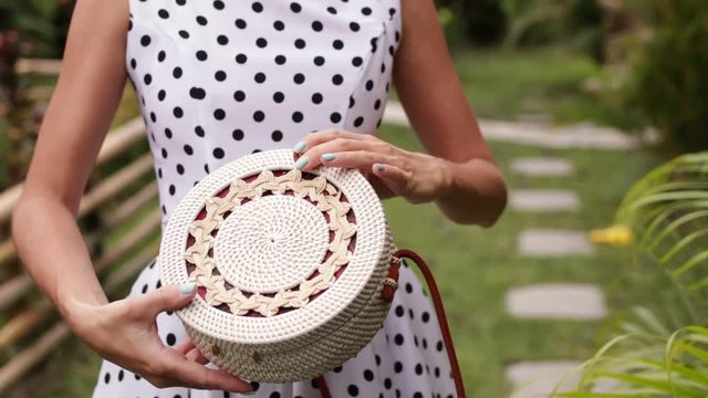 Closeup of stylish rattand handbag in the tropical garden.