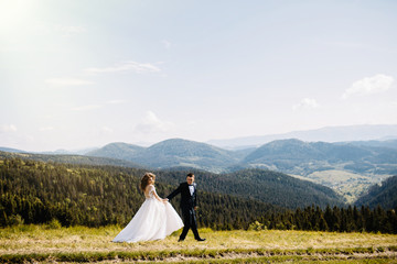 Romantic couple newlyweds posing at sunset on a background of mountains.