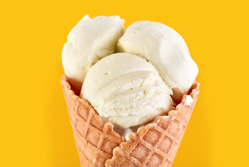 ice cream balls with colored sugar sprinkles in a Waffle Cone on a yellow Background. Vanilla ice cream in a waffle cone.