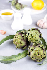 Fresh artichoke preparing for cooking with garlic, lemon and olive oil, kitchen interior.