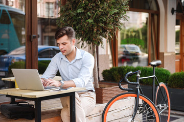 Confident young stylish man working on laptop computer