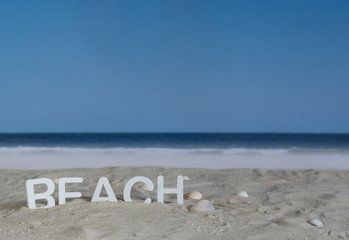 The word beach in white wooden letters in the sand on the beach