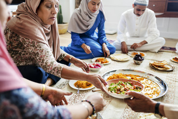 Muslim family having dinner on the floor - obrazy, fototapety, plakaty