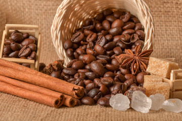 Coffee beans and cinnamon on a background of burlap. Roasted coffee beans background close up. Coffee beans pile from top with copy space for text. Seasoning. Spice. Cinnamon. Badian. Coffee house.